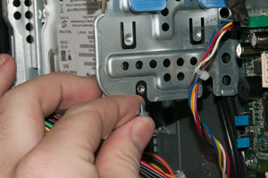 Tightening first screw to secure hard drive